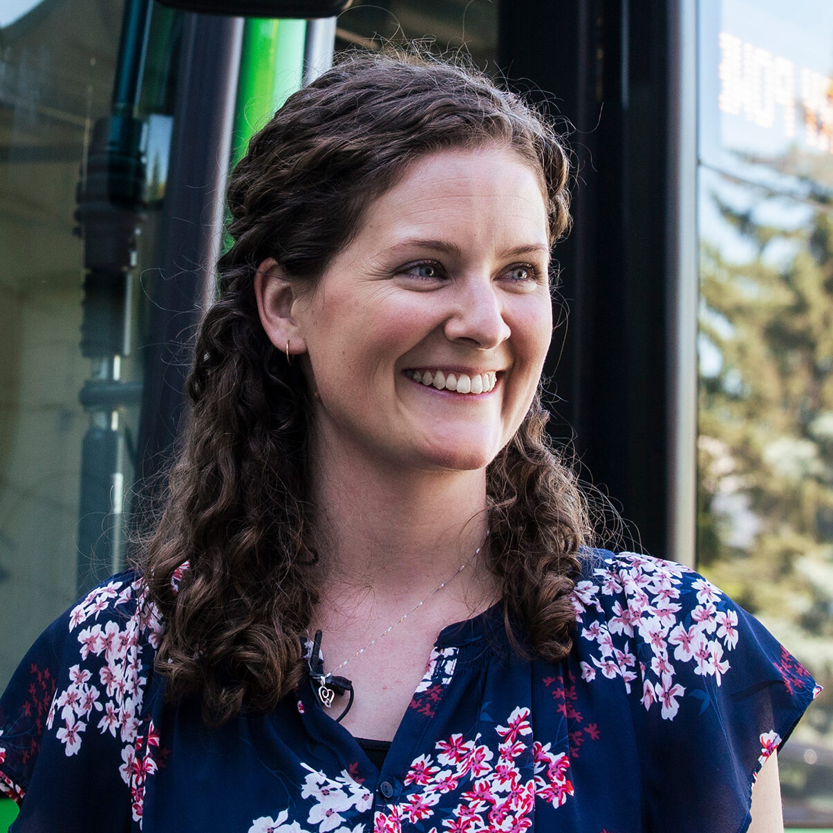 Smiling woman standing near green bus.