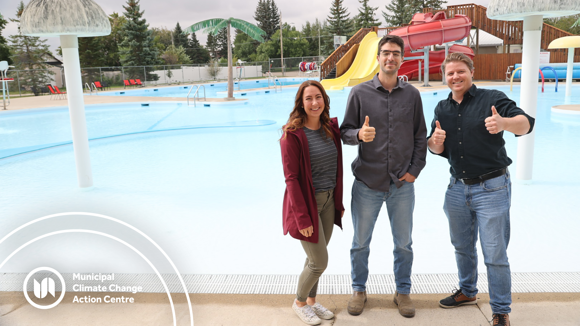 Municipal staff stand in front of an outdoor pool in Raymond
